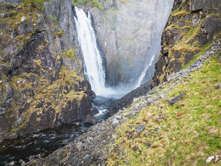 Obraz premium Stunning aerial drone view of a massive waterfall plunging into a deep, rocky canyon in the scenic landscape of Norway.