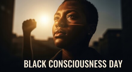 Person of color raising fist celebrating Black Consciousness Day, symbol of awareness and unity, warm light glow