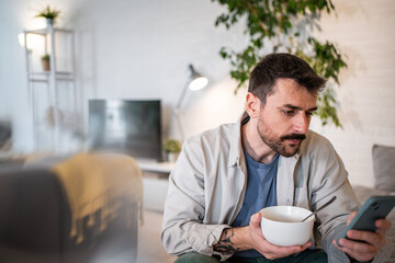 Man multitasking having breakfast and checking phone