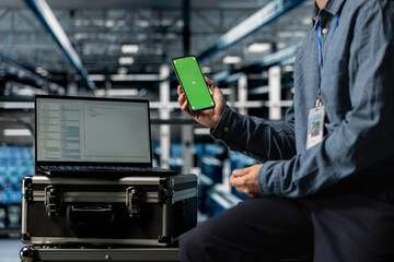 Close up of server hub computer scientist using chroma key mobile phone, waiting for code to finish compile. Data center worker checking mobile applications on isolated screen smartphone to unwind