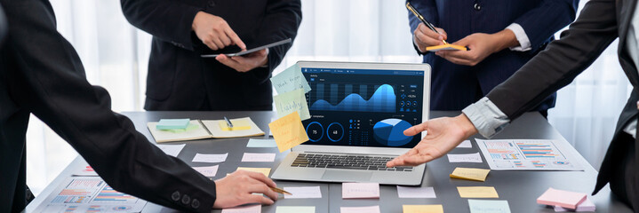 Analyst team use sticky note for creative and analytic brainstorm for business idea with BI data dashboard on laptop screen. Analysis financial data visualization tech for marketing strategy. Prodigy