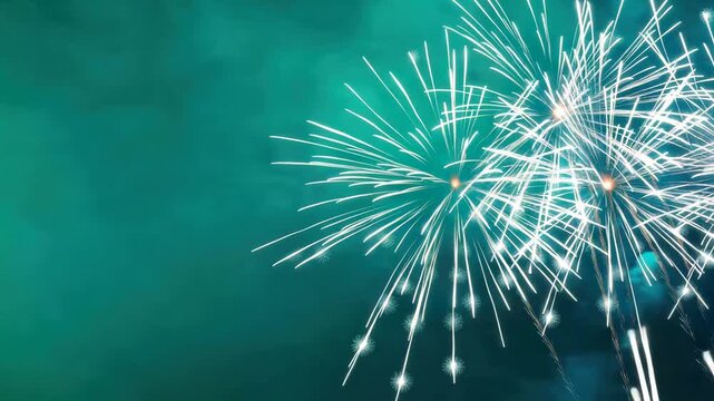Bright white fireworks bursting in the night sky against a teal blue background. 4K video