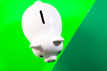 White piggy bank on a green background. Saving money concept.