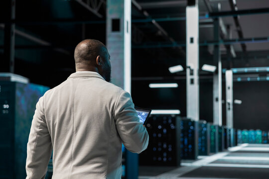 Server hub software developer uses machine learning on device to predict future gear needs. Data center computer scientist using AI neural networks tech on tablet to enhance operational effectiveness.