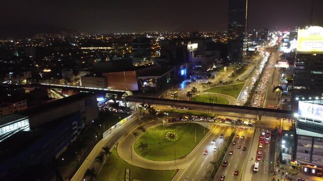 Aerial view of a major highway intersection with heavy traffic and a train passing by at night