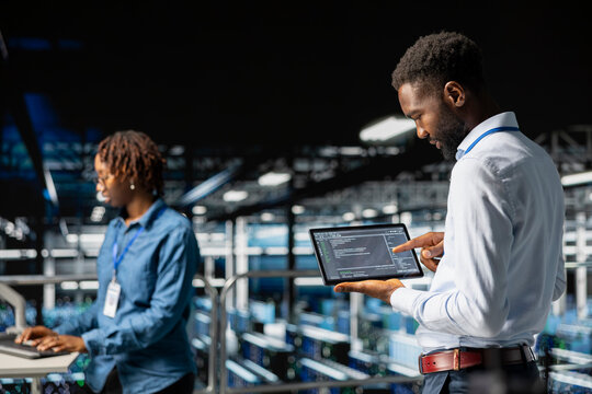 Staff of data scientists on modern industrial platform analyzing neural network after troubleshooting software updates. Server room technicians finetuning algorithms IT configurations.