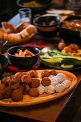 Vegan cocoa and coconut energy balls on wooden platter with vegetable snacks on a rustic table