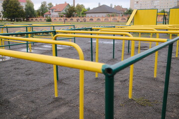 Fototapeta premium Close view shows yellow and green metal monkey bars on the playground in the daytime.