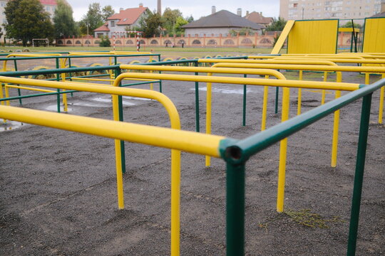 Close view shows yellow and green metal monkey bars on the playground in the daytime.