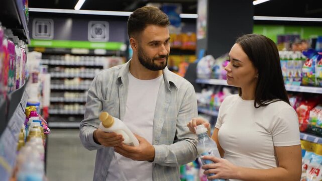 Young couple choosing fabric softener in supermarket