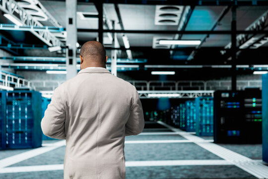 Admin walking in high tech data center, doing checkup to prolong equipment life span and increase uptime. African american server hub IT expert monitoring infrastructure mainframes, upgrading systems