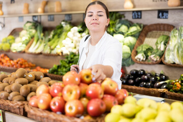 Portrait of happy young female customer selecting fruits in grocery store