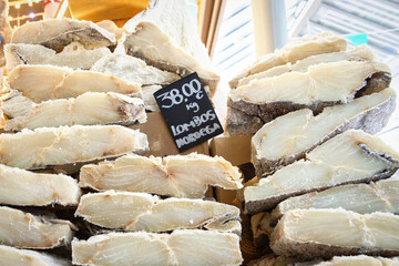 A large stack of premium, thick-cut, salted and dried codfish (Bacalhau) fillets on display with a handwritten price tag at the Mercado do Bolh&atilde;o in Porto