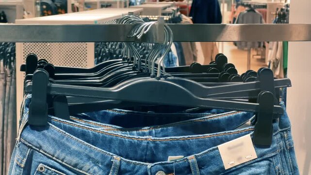 Blue Denim Jeans Hanging on Black Hangers in Clothing Store Display | Front View of New Pants on Retail Rack | Fashion Shopping Interior