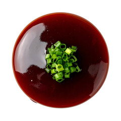 Overhead view of a glossy, dark sauce topped with a small pile of finely chopped green onions