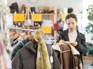 Fototapeta premium Woman chooses checkered jacket searches for fashionable clothes in a clothing boutique