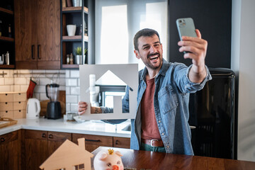 Happy man taking selfie with house cutout