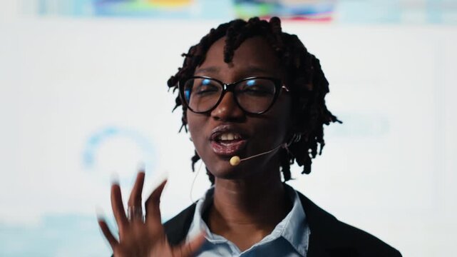 Close up of manager leads visionary business pitch at event, showing performance metrics graphs on screen to inspire audience. Businesswoman doing public speaking at convention, holding speech