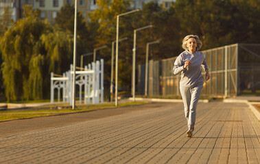 Senior woman jogging outdoors in park reflects active lifestyle and wellbeing. Regular running...