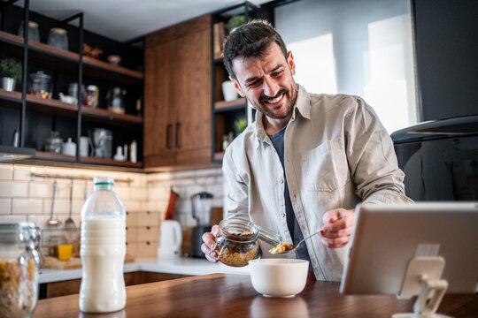 Man enjoying breakfast while watching content on tablet