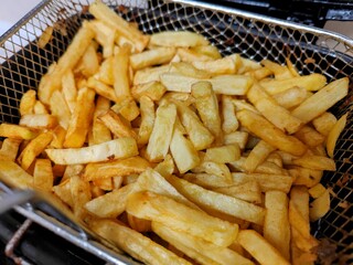 Golden French fries in a metal basket. Close-up view.