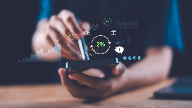 A person uses a smartphone to analyze digital finance and interest rate growth with futuristic data visualization. Concept of investment, saving, profit, and fintech innovation in modern economy.