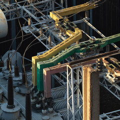 Detailed view of a high voltage substation featuring color-coded insulators and metal conductors...