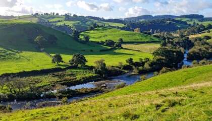 Obraz premium Peaceful landscape showcases rolling green hills under a partly cloudy sky, a flowing river winds through the valley, with scattered trees adding depth to the natural setting, creating a serene and...