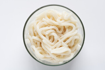 Top view of a clear glass bowl filled with thick, glossy, plain white Udon noodles.
