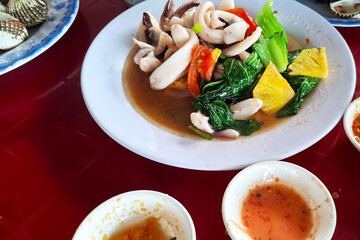 Delicious Asian Seafood Dish With Calamari And Vegetables Served In A White Plate With Dipping Sauces