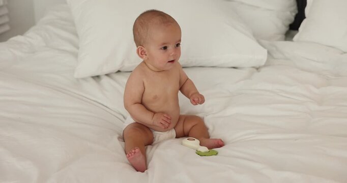Cute little baby with toy on bed at home