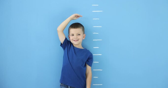 Little boy measuring his height near blue wall