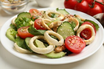 Delicious salad with squid rings and ingredients on white table, closeup