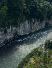 A serene river winds through steep cliffs, surrounded by vibrant trees and calm waters