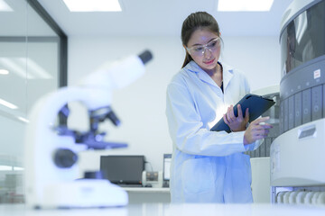 Naklejka premium A laboratory manager reviews the entire workflow, using a tablet to analyze data from microscopy and a high-throughput analyzer, optimizing the process for maximum efficiency.