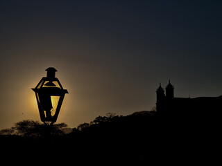 Silhouette of a church and a lamppost during sunset in the historic city of Ouro Preto in Brazil