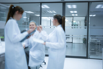 Fototapeta premium A team of female scientists shares a positive, collaborative moment in a spacious and modern laboratory, representing a healthy and productive work culture in the field of science.