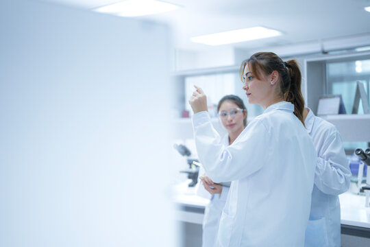 A scientist uses an augmented reality system to share a live microscopic view of a slide with remote colleagues, enabling real-time global consultation and AI-assisted analysis.