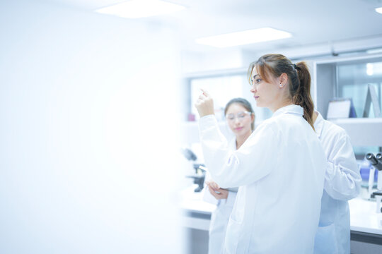 A pathologist presents a challenging case to her colleagues, holding up a histology slide and discussing the cellular morphology to reach a collaborative diagnostic consensus.