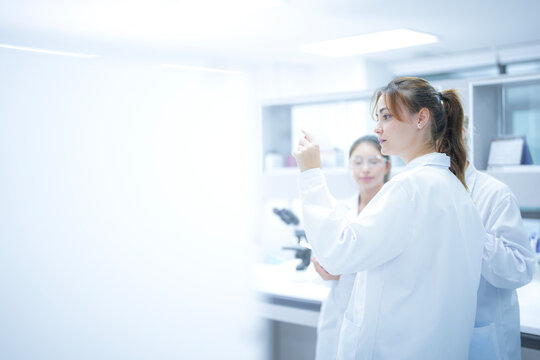 A scientist uses an augmented reality system to share a live microscopic view of a slide with remote colleagues, enabling real-time global consultation and AI-assisted analysis.