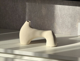 A modern cream-colored ceramic vase sits on a bright surface, illuminated by sunlight