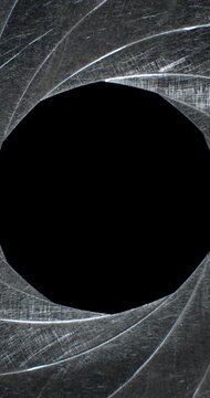 Circular blades of a mechanical iris create a precision opening controlling amount of light entering a camera lens with the opening mechanism controlling the aperture and the depth of field in focus.