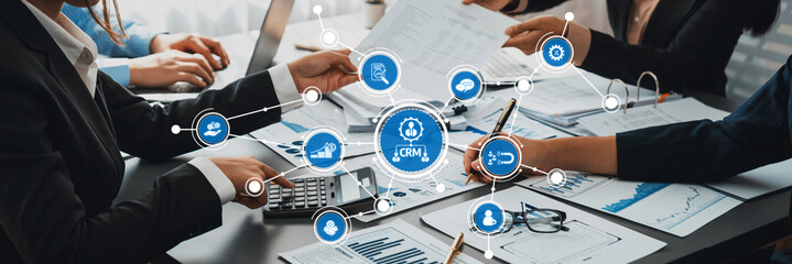 A professional team engaged in a collaborative effort to improve CRM strategies, utilizing digital tools and analyzing data in a modern office setting for enhanced outcomes. Amity