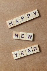 Wooden letter tiles arranged to spell HAPPY NEW YEAR on a brown textured background