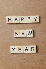 Wooden letter tiles arranged to spell HAPPY NEW YEAR on a brown textured background