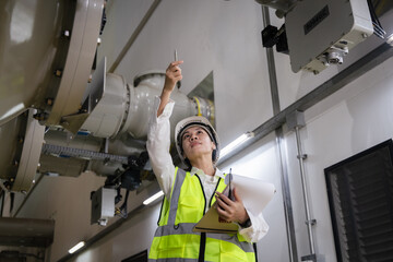 inspecting high-voltage gas-insulated switchgear (GIS), Female engineer in safety helmet, reflective vest inside a power plant, taking notes on clipboard, symbol of industrial safety, professionalism
