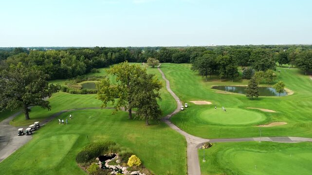 Drone view of the golf course and players with the golf carts on it. Active pastime. Type of sport for rich people
