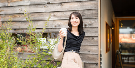 カフェでテイクアウトのコーヒーを持つ女性