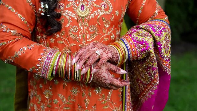 Close up view of Traditional Indian or Pakistan henna painted bridal hands with wedding rings. Bride playing with her bangles on the hands