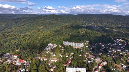 Aerial view of serene forest and mountains, with a cozy residential area for peaceful retreats